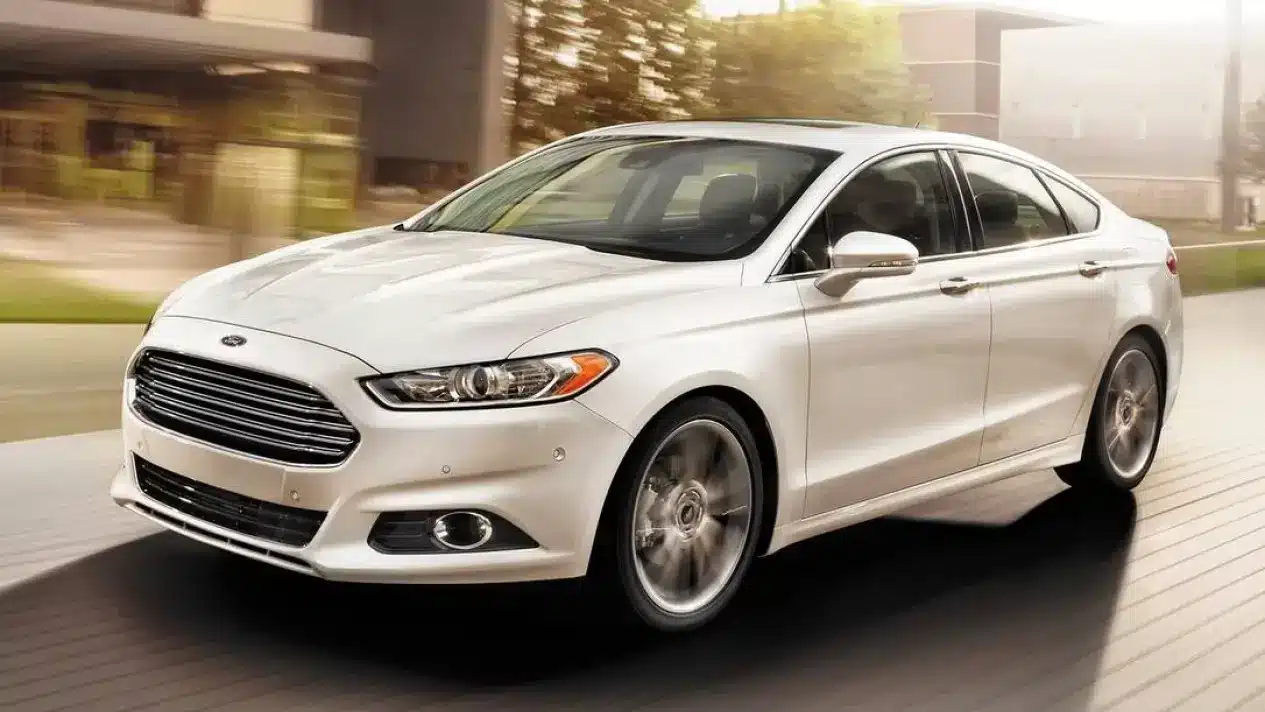 A sleek white Ford Fusion sedan driving through the city, emphasizing its stylish look and strong performance.