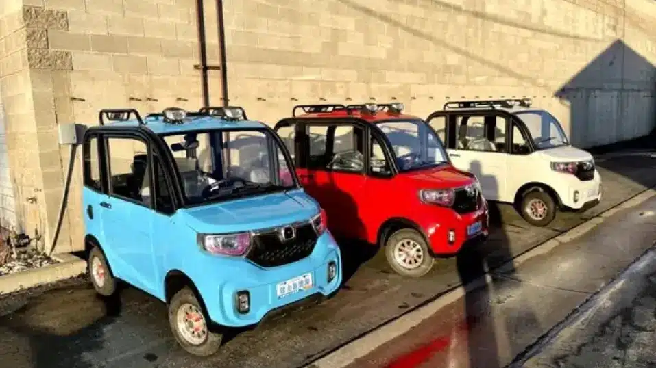 Three Changzhou ChangLi S1-Pro micro electric vehicles parked in a row, featuring blue, red, and white models, showcasing the compact and affordable design of the world's cheapest car of 2024.