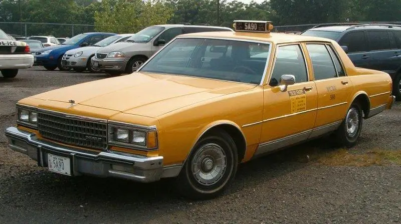 A classic yellow Chevrolet Caprice from the 1980s parked in a lot, reflecting its iconic status in Georgia.