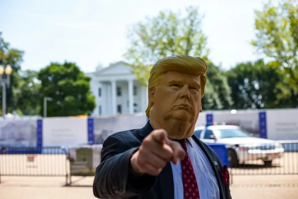 A caricature figure of Donald Trump pointing assertively, with the White House blurred in the background, symbolizing the 100% tariff plan on Chinese cars made in Mexico.