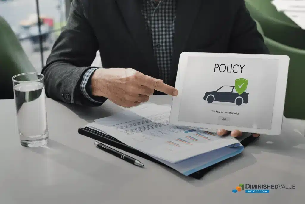 A professional insurance appraiser points to a tablet screen with a 'POLICY' icon, symbolizing the expertise and guidance provided by Diminished Value of Georgia in navigating auto insurance policies and claims.