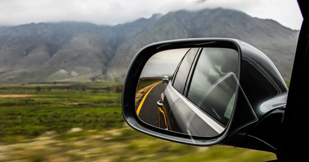 car mirror with another car in the back following him