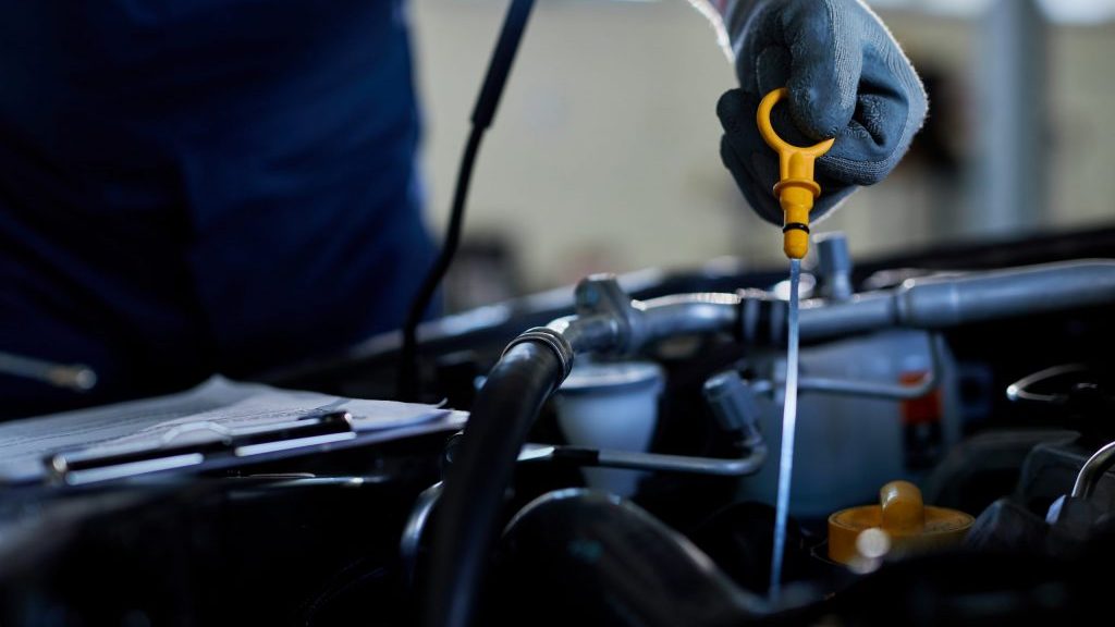 Close-up of a auto repairman checking car oil in a workshop