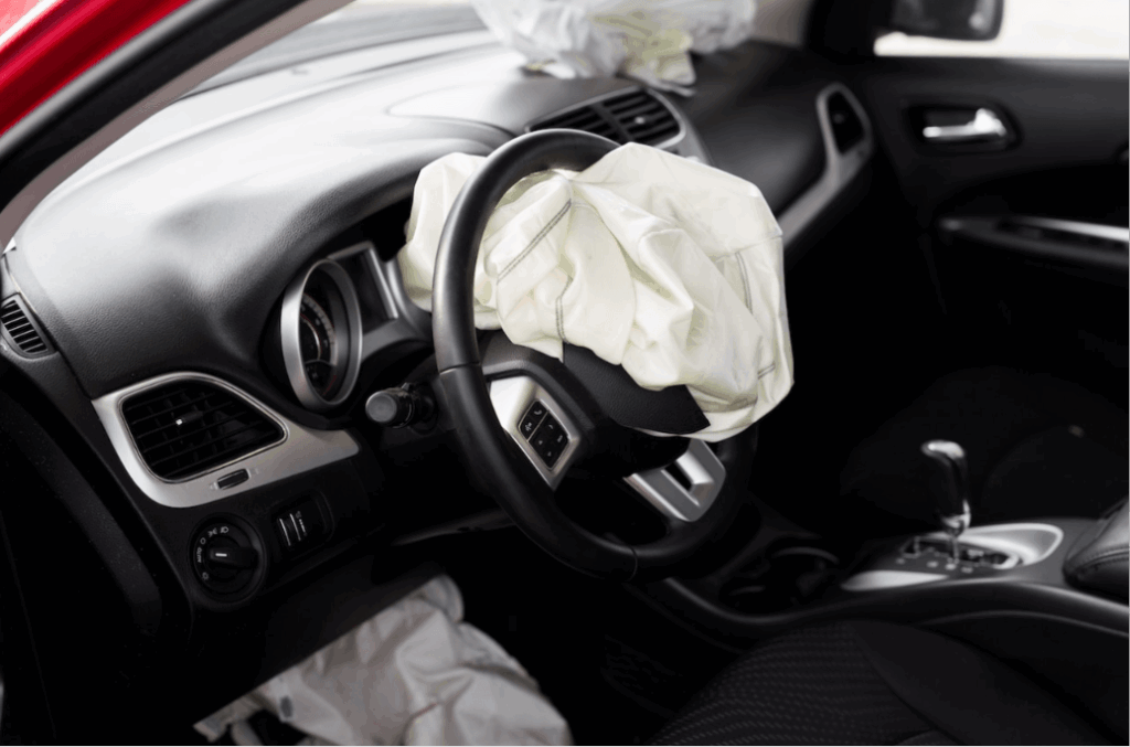 Current image: Driver-side airbag has deployed in the car, with the steering wheel wrapped in the white bag and interior dashboard visible during a crash scenario