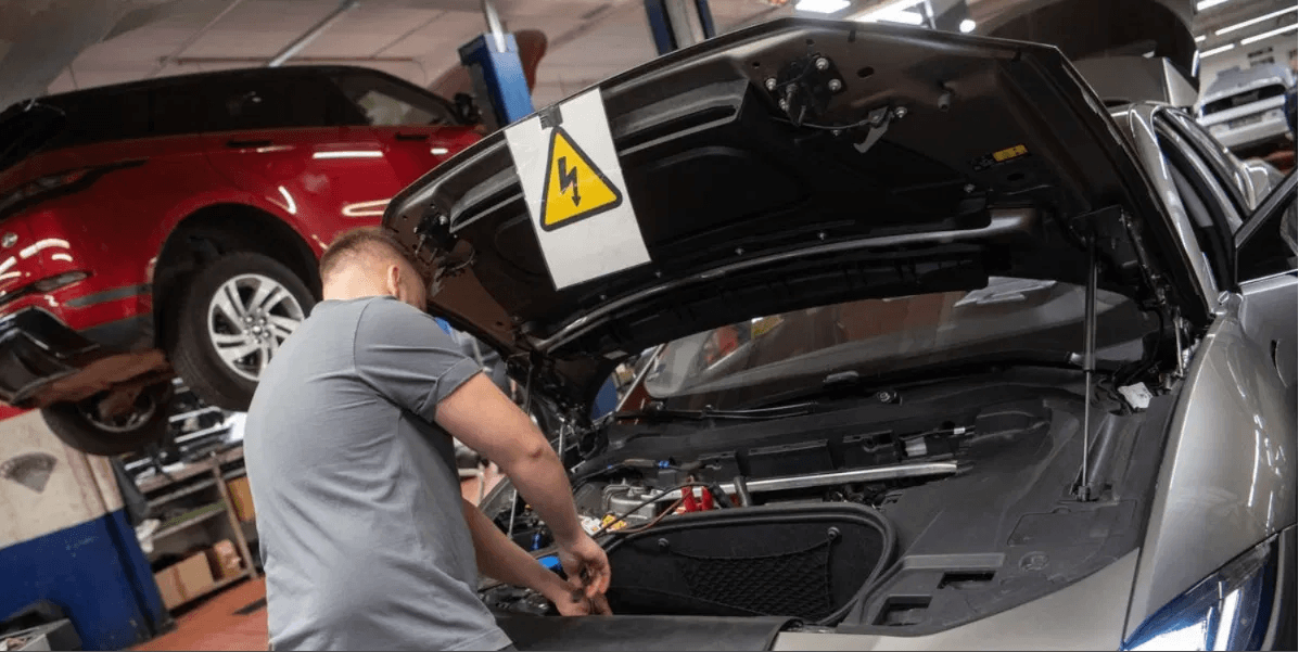 Hybrid Vehicle Collision Repair in Auto Body Shop – Diminished Value of Georgia, Car Appraisals for Insurance Claims Mechanic inspecting hybrid vehicle high-voltage system under the hood at a collision repair shop in Georgia | Diminished Value of Georgia, Car Appraisals for Insurance Claims