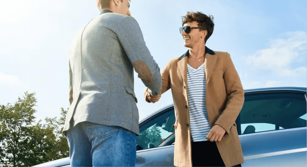 Two men shaking hands during a private car sale in Georgia – Diminished Value of Georgia, Car Appraisals for Insurance Claims Two men shaking hands next to a car during a private sale, illustrating the impact of accident history on vehicle resale value in Georgia | Diminished Value of Georgia, Car Appraisals for Insurance Claims